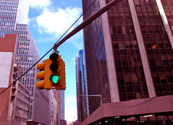 This is an upward facing photograph of a green streetlight with blue sky behind it.